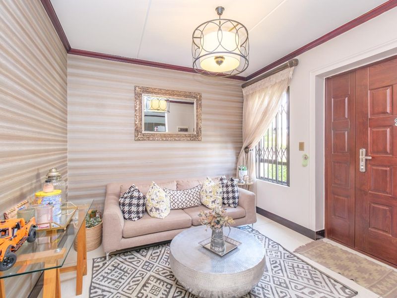 Welcoming entrance area featuring a solid wood front door, secure window grille, and decorative ceiling lighting, creating a warm and inviting first impression.
