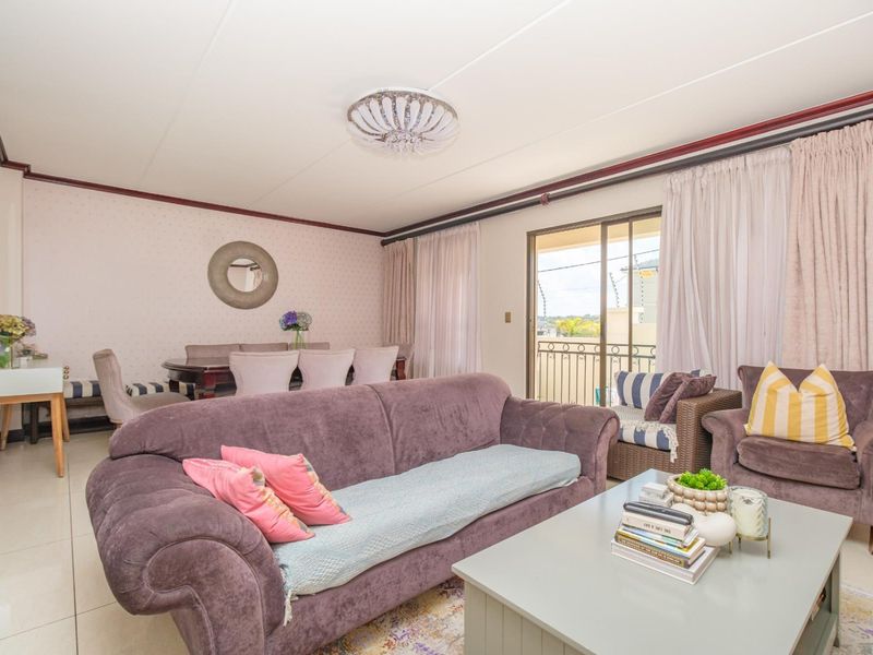 Open-plan living and dining area featuring tiled flooring, crown molding, and a sliding glass door providing access to the balcony.