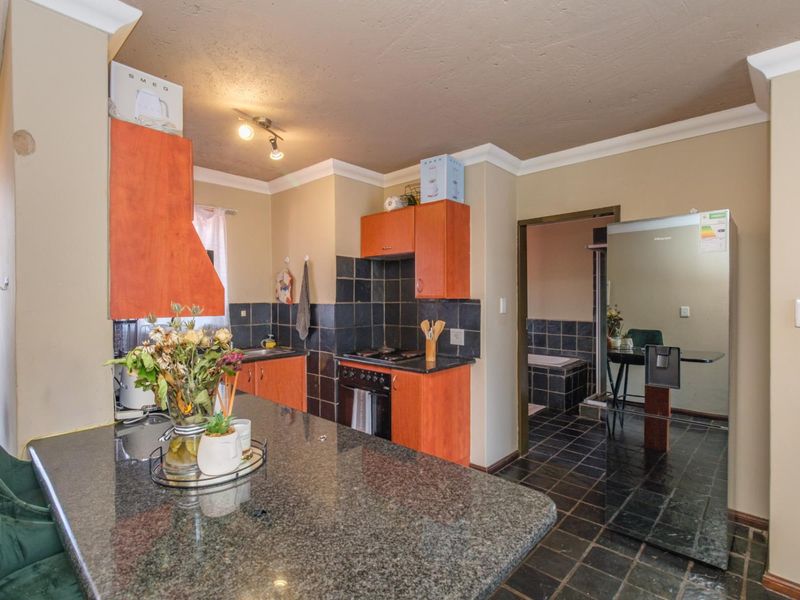 Kitchen featuring granite countertops, built-in cabinetry, and a tiled backsplash, with an adjacent view into the bathroom area.