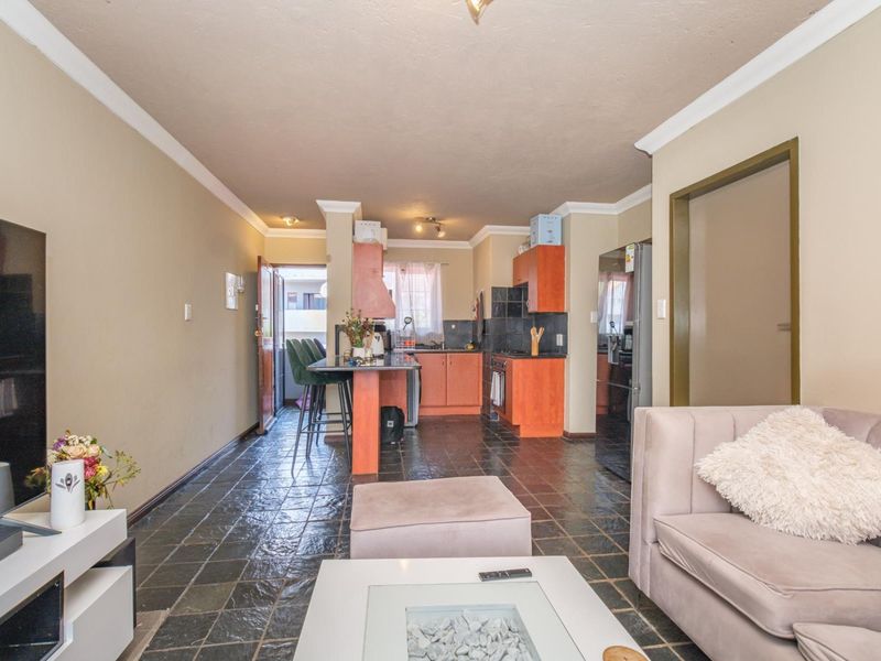 Open-plan living and kitchen area featuring dark stone tile flooring, built-in cabinetry, and a breakfast bar, creating a functional and connected living space.