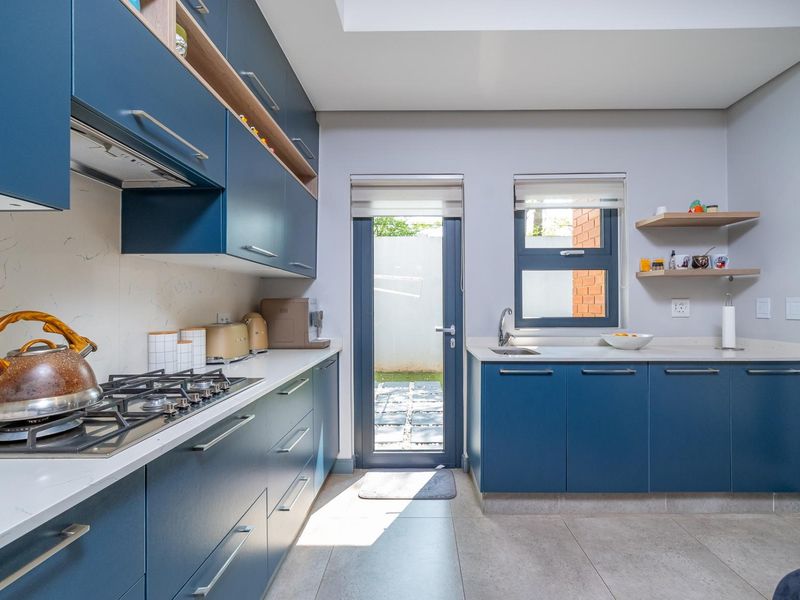 Modern kitchen featuring navy blue cabinetry, stone countertops, gas hob, extractor fan, and direct access to an outdoor area.