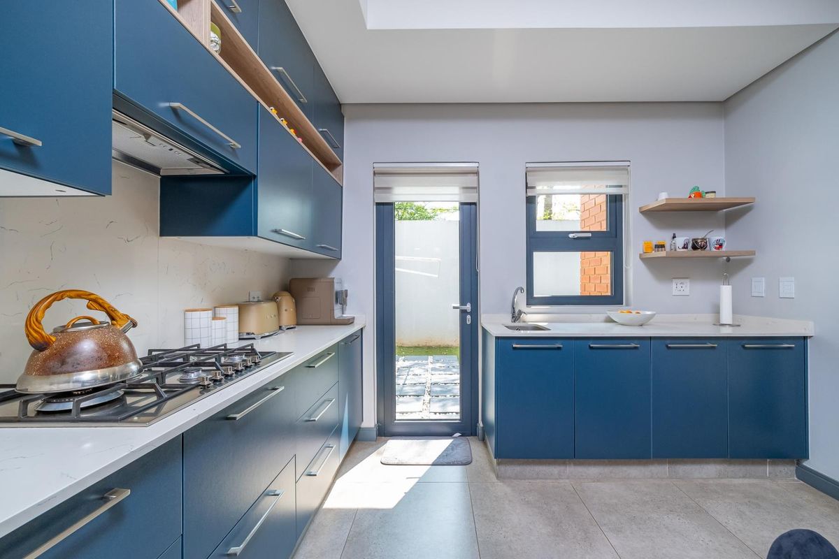 Modern kitchen featuring navy blue cabinetry, stone countertops, gas hob, extractor fan, and direct access to an outdoor area.