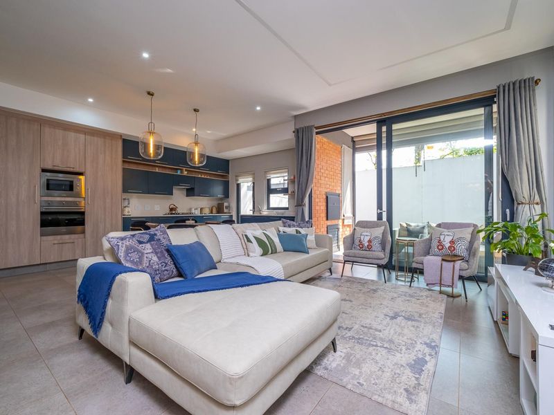Modern open-plan living area featuring a contemporary kitchen with built-in appliances, tiled floors, and large sliding doors opening to an outdoor space.