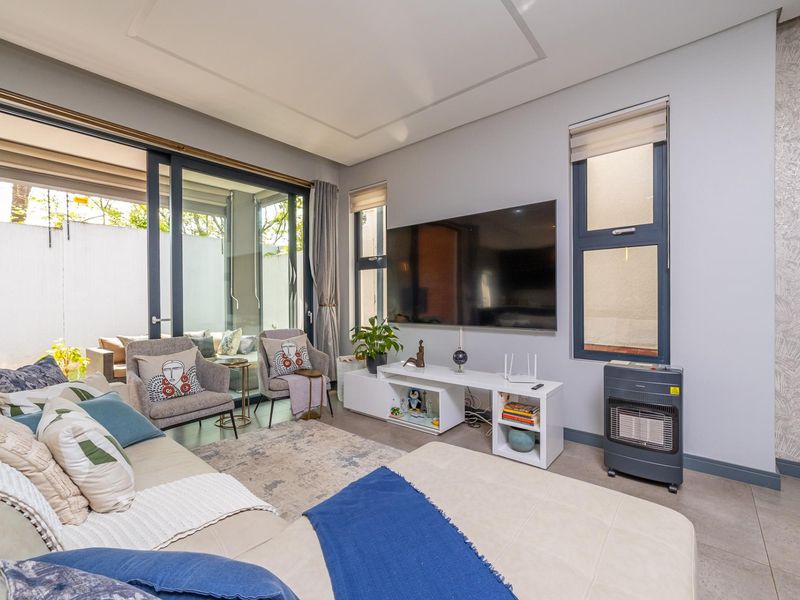 Modern living room featuring large sliding glass doors leading to an outdoor area, tiled flooring, and recessed ceiling detailing.