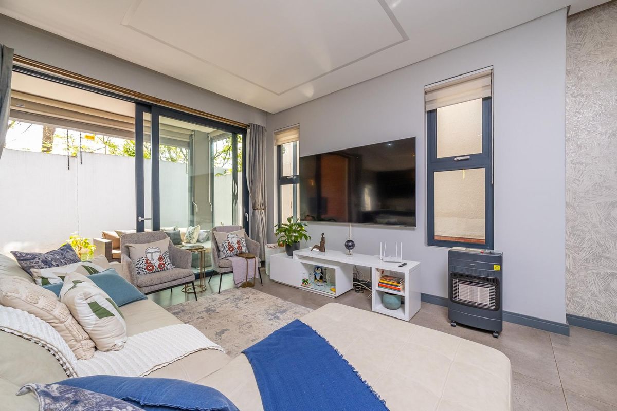 Modern living room featuring large sliding glass doors leading to an outdoor area, tiled flooring, and recessed ceiling detailing.