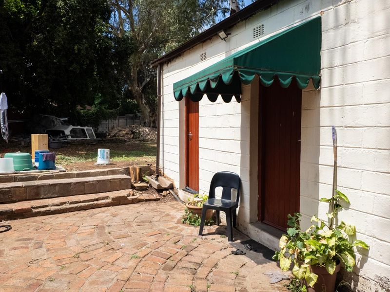 Rear exterior view of the property featuring a brick paved patio area, stone steps, and a fabric awning over the timber entrance doors.