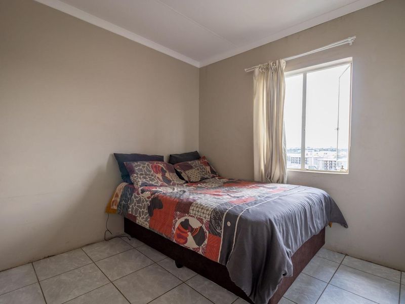A functional bedroom featuring tiled flooring and a window with natural light, providing a simple and practical living space.