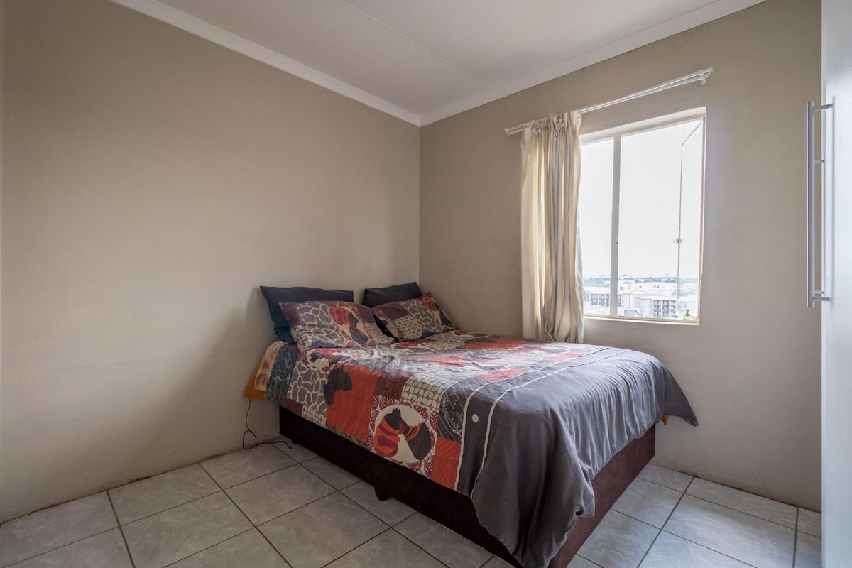 A functional bedroom featuring tiled flooring and a window with natural light, providing a simple and practical living space.