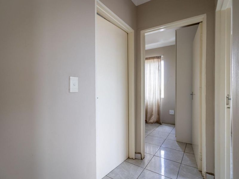 A functional hallway featuring tiled flooring and access to adjacent rooms, showing standard wear and tear.