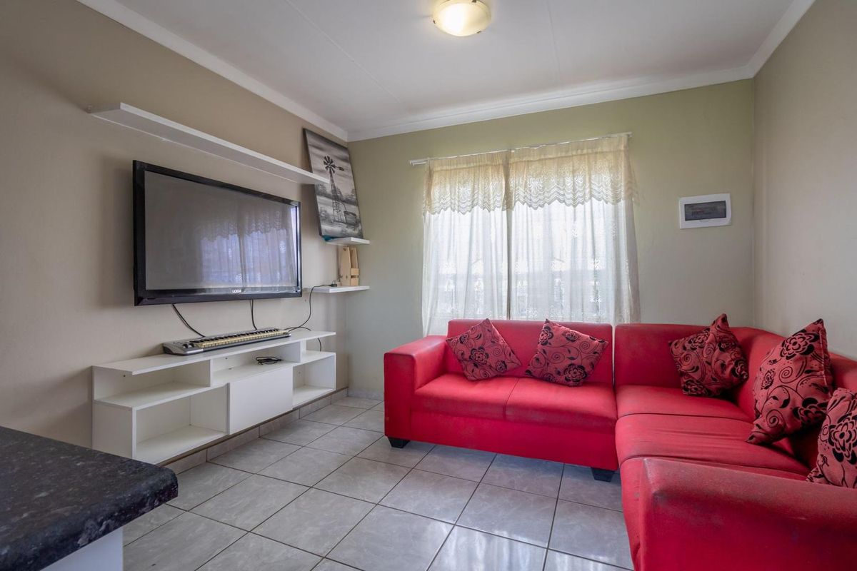 A functional living room featuring tiled flooring and wall-mounted shelving, providing a practical space for relaxation.