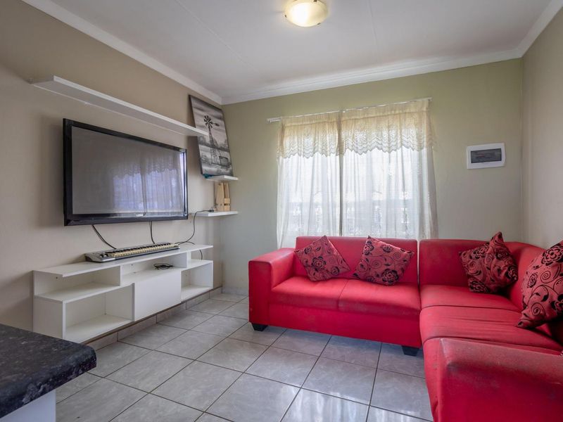 A functional living room featuring tiled flooring and wall-mounted shelving, providing a practical space for relaxation.