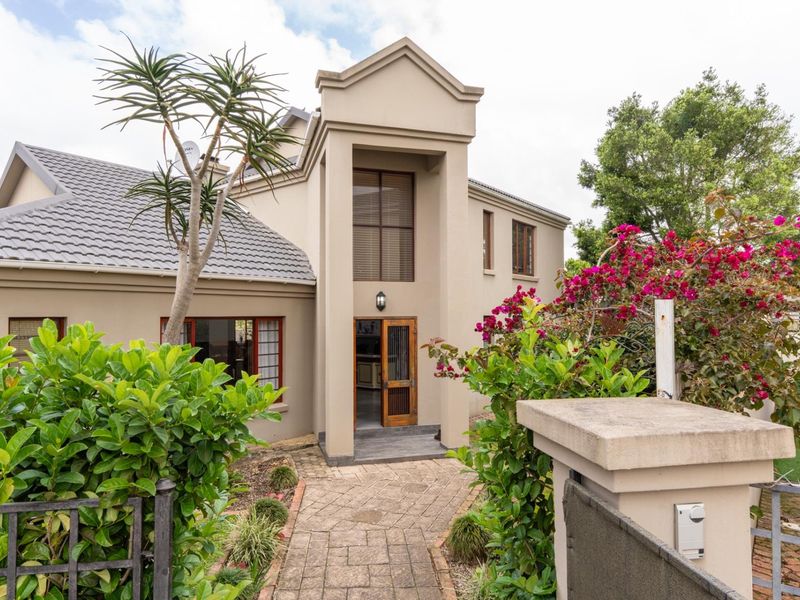Front elevation of a double-story residence featuring a paved walkway, landscaped garden, and a prominent timber entrance door.