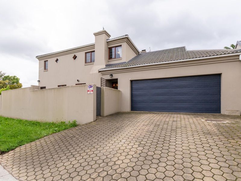 Front exterior view of the property featuring a paved driveway, double garage, and secure boundary wall.