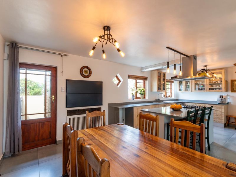 Open-plan kitchen and dining area featuring a central island, built-in cabinetry, gas hob, and tiled flooring with direct access to the exterior.
