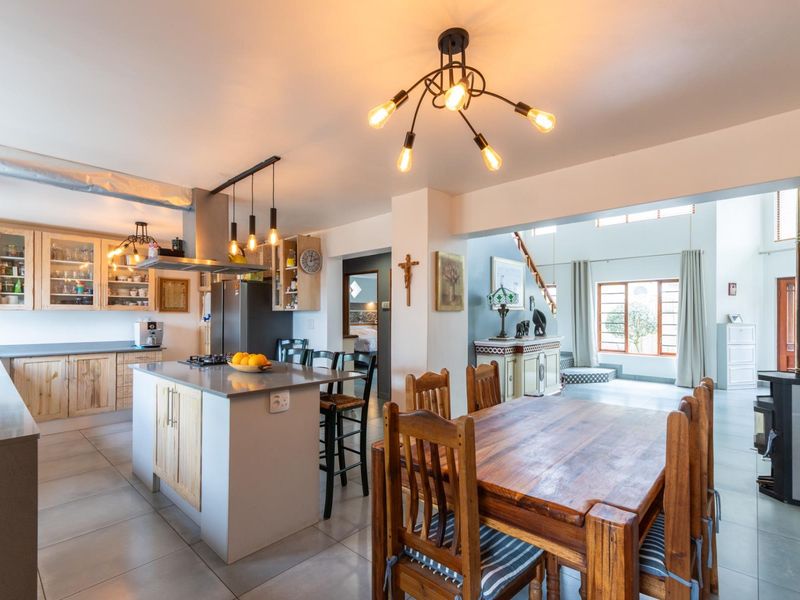 Spacious open-plan kitchen and dining area featuring a central island, modern cabinetry, tiled floors, and a cozy wood-burning stove in the adjacent living space.
