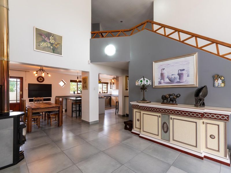 Spacious open-plan living and dining area featuring tiled floors, a modern fireplace, and a staircase leading to the upper level.