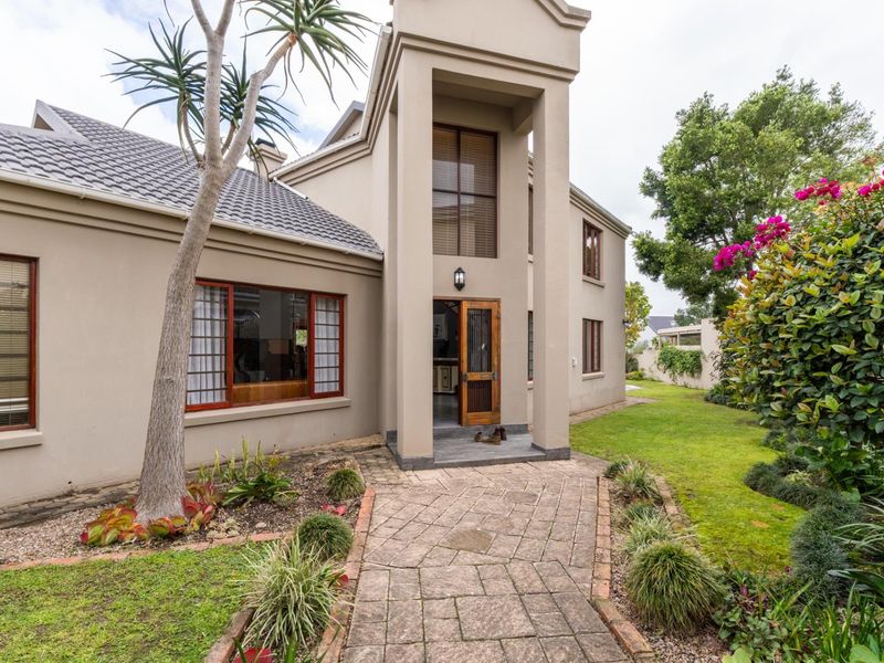 A well-maintained front entrance featuring a paved walkway, landscaped garden, and a prominent architectural facade with a tiled roof.