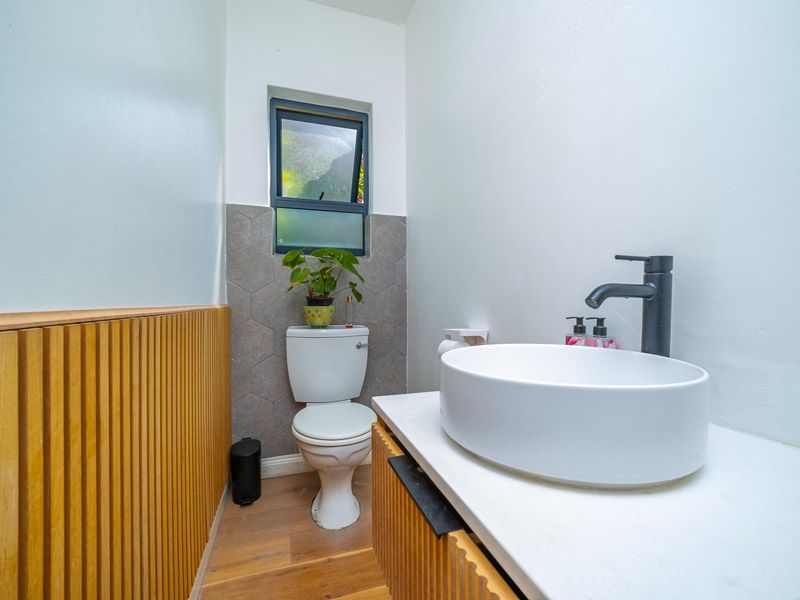 Modern bathroom featuring a vessel sink with a black faucet, timber slat wall paneling, and stylish hexagonal tile accents.