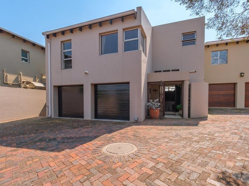 Front elevation of a modern townhouse featuring a double garage, paved driveway, and secure entrance.