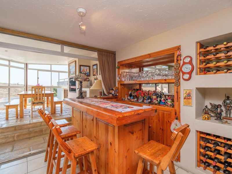 A dedicated bar area featuring a built-in wooden counter, integrated wine storage shelving, and direct access to an enclosed patio space.
