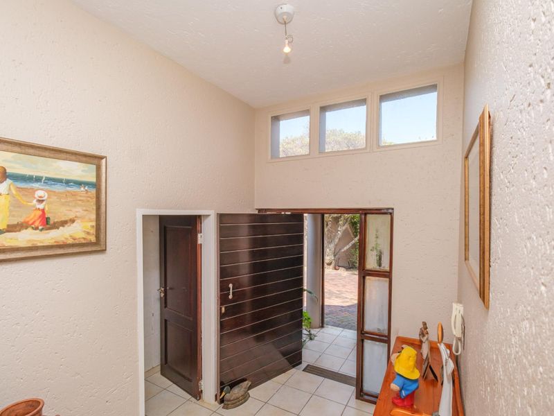 Entrance hall featuring textured walls, tiled flooring, and clerestory windows that provide natural light, leading to a solid timber front door.