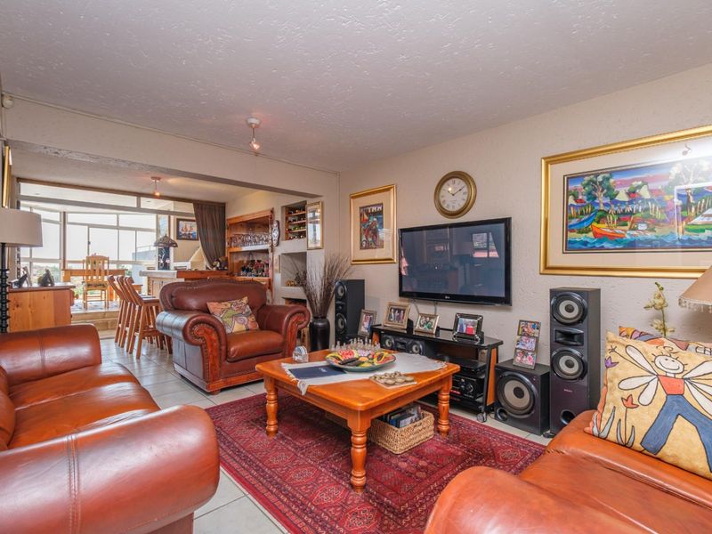 Open plan living area featuring tiled floors and a seamless transition to an enclosed patio space with built-in storage and shelving.