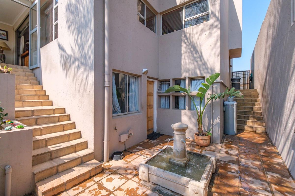 Rear courtyard area featuring a stone fountain, tiled staircases leading to upper levels, and exterior access points.