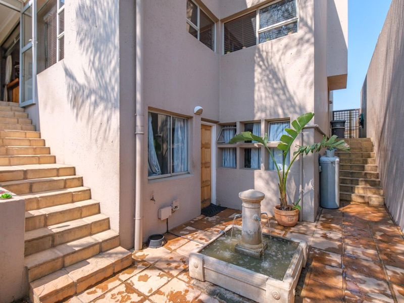 Rear courtyard area featuring a stone fountain, tiled staircases leading to upper levels, and exterior access points.
