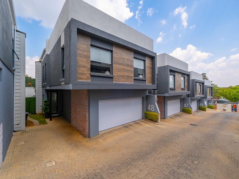 Modern multi-unit residential complex featuring contemporary architectural design, paved driveway access, and integrated sectional garage doors.