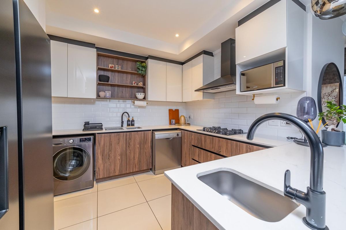 Modern kitchen featuring wood-grain and white cabinetry, quartz countertops, subway tile backsplash, gas hob, extractor fan, and integrated appliances.