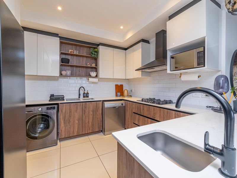 Modern kitchen featuring wood-grain and white cabinetry, quartz countertops, subway tile backsplash, gas hob, extractor fan, and integrated appliances.