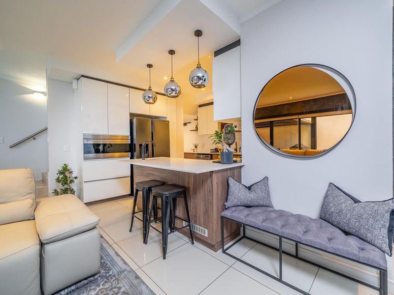 Modern open-plan living area featuring a sleek kitchen with built-in cabinetry, stone-topped island, and contemporary pendant lighting, seamlessly integrated with the living space.