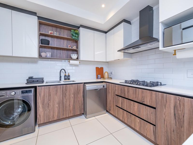 Modern kitchen featuring wood-grain and white cabinetry, subway tile backsplash, stone countertops, gas hob, extractor fan, and integrated appliances.