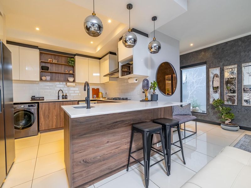 Modern kitchen featuring a central island with quartz countertops, sleek cabinetry, subway tile backsplash, and integrated appliances, complemented by stylish pendant lighting.