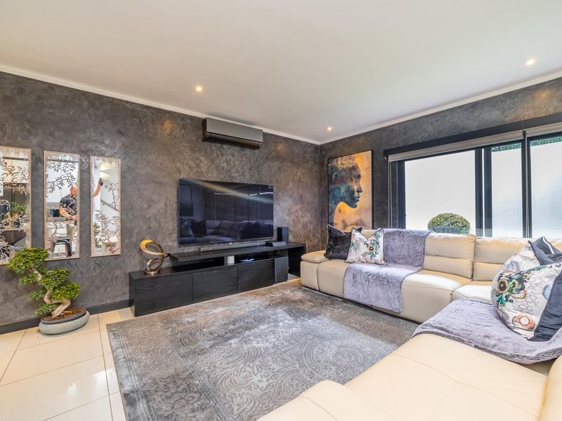 Modern living room featuring a textured feature wall, tiled flooring, recessed downlighting, and a wall-mounted air conditioning unit.