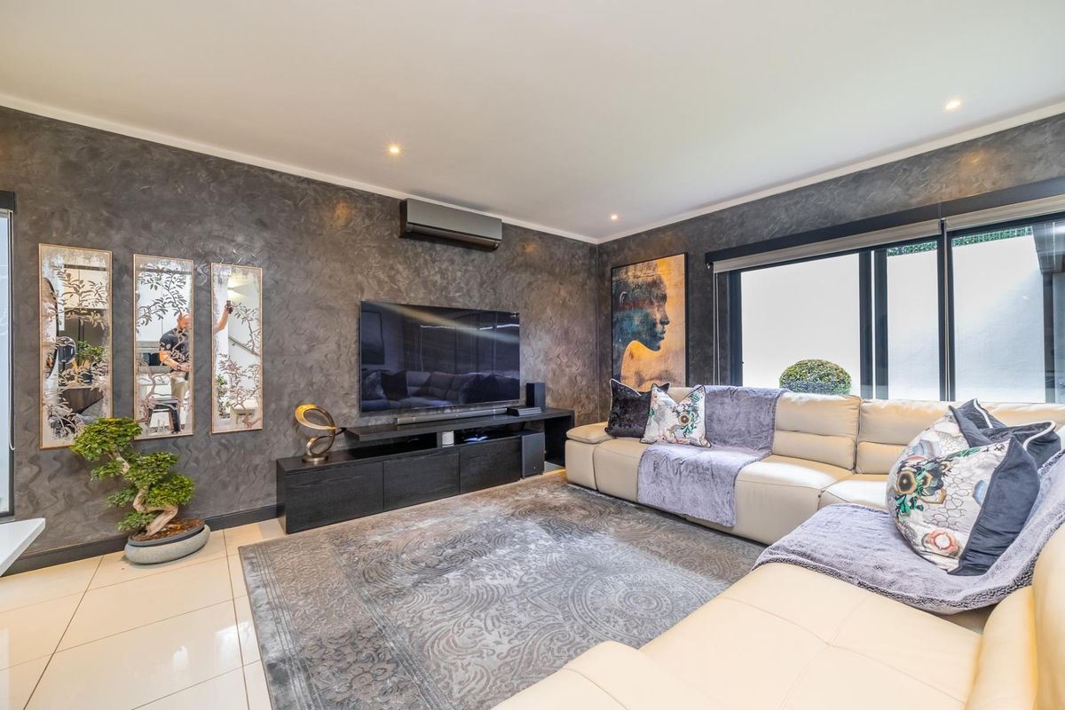 Modern living room featuring a textured feature wall, tiled flooring, recessed downlighting, and a wall-mounted air conditioning unit.