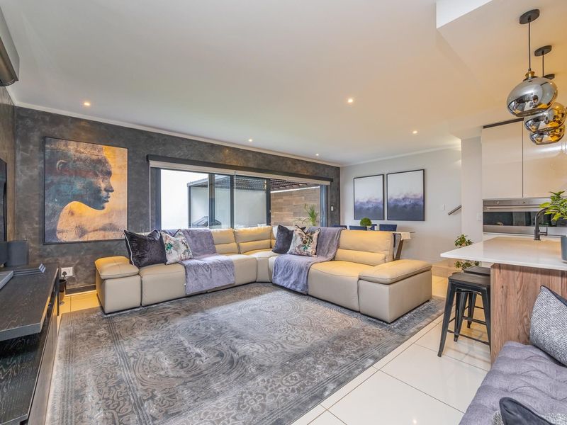 Modern open-plan living area featuring a sleek kitchen with island, tiled floors, recessed lighting, and large sliding doors leading to an outdoor space.