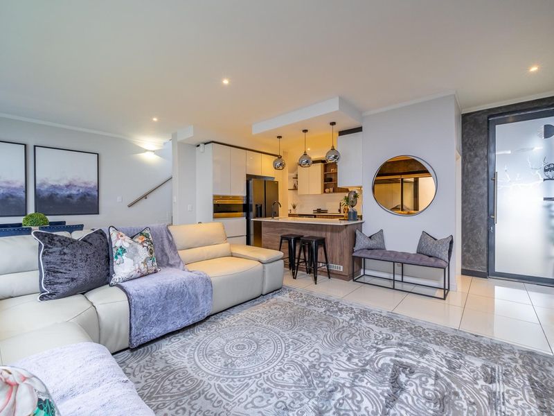 Modern open-plan living area featuring a sleek kitchen with island, recessed lighting, and high-quality tiled flooring, seamlessly connecting to the main living space.
