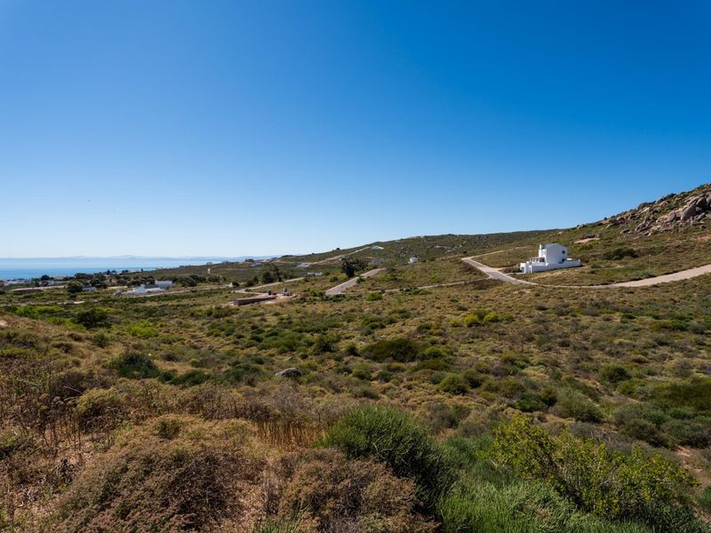 A wide-angle view of the vacant residential land, showcasing the natural coastal landscape, surrounding terrain, and distant ocean horizon.