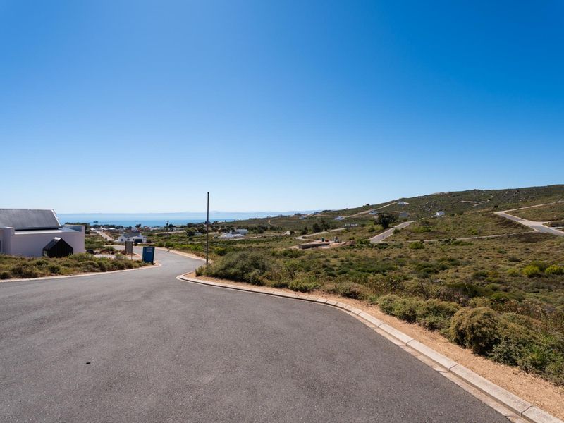 A view of the paved residential street and surrounding landscape, showcasing the neighborhood approach and coastal terrain.