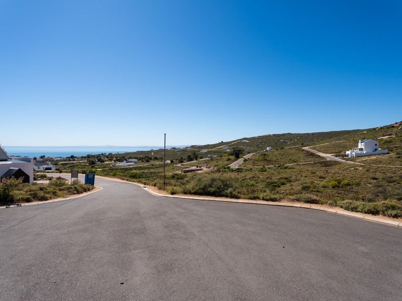 A clear street view of the residential development area, featuring paved roads, concrete curbing, and surrounding coastal landscape.