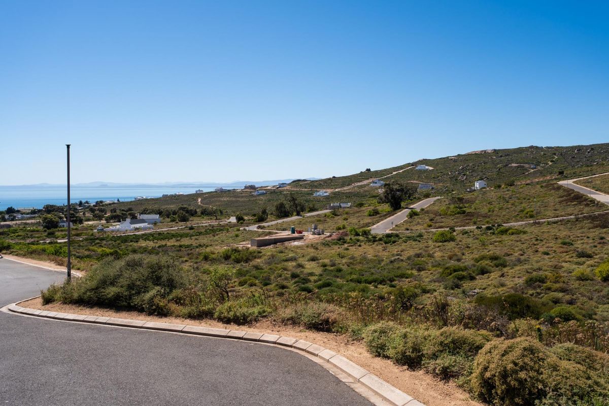 A scenic elevated view of a coastal residential development area featuring paved roads, natural vegetation, and distant ocean vistas.