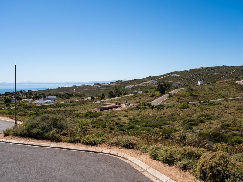 A scenic elevated view of a coastal residential development area featuring paved roads, natural vegetation, and distant ocean vistas.