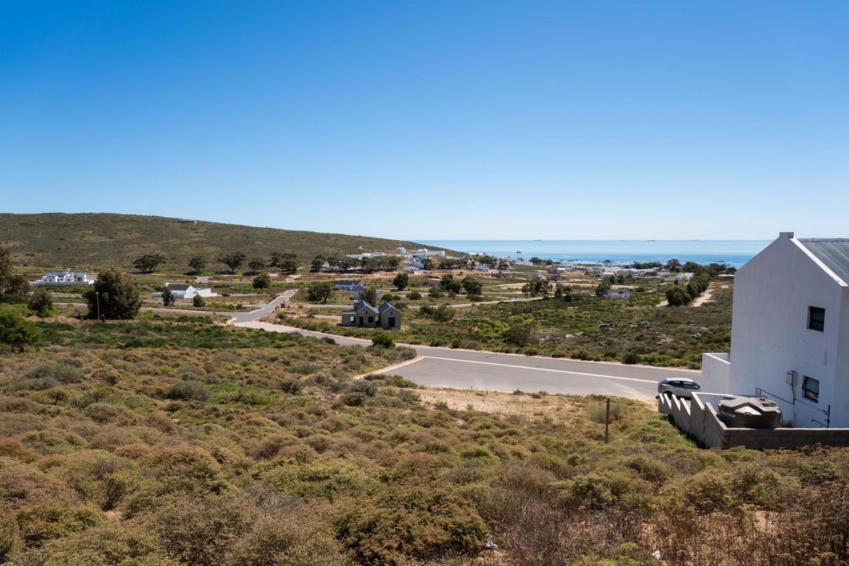 An elevated view of the surrounding coastal landscape, showing local residential development, paved roads, and the ocean in the distance.