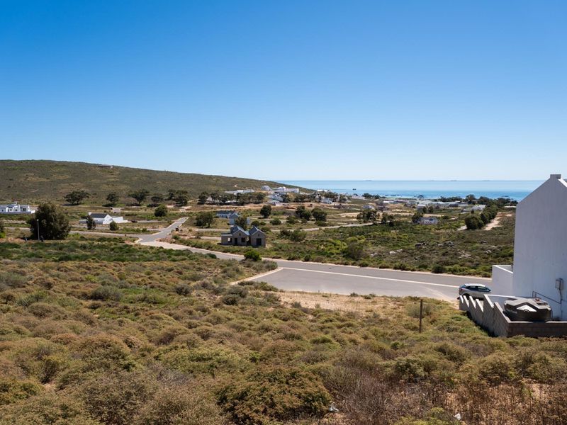 An elevated view of the surrounding coastal landscape, showing local residential development, paved roads, and the ocean in the distance.