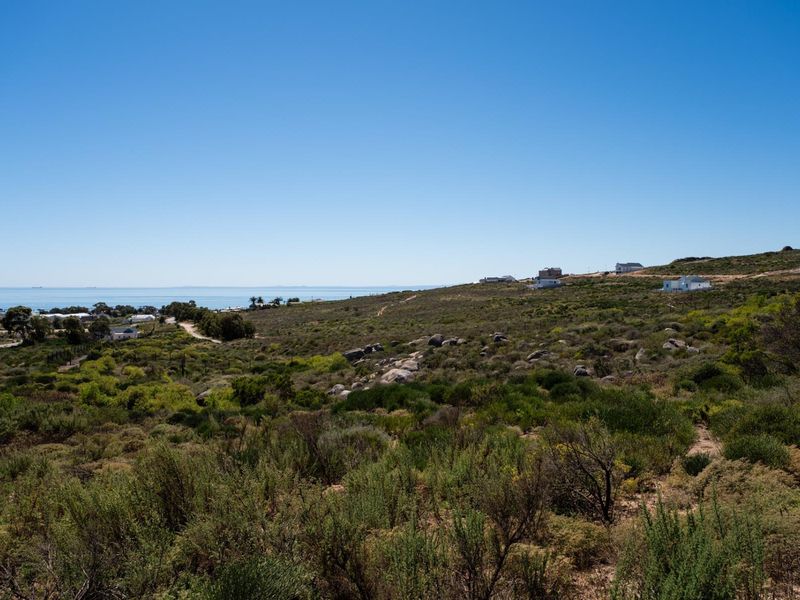 A scenic view of the coastal landscape featuring natural vegetation, rock formations, and distant ocean views from the vacant residential land.