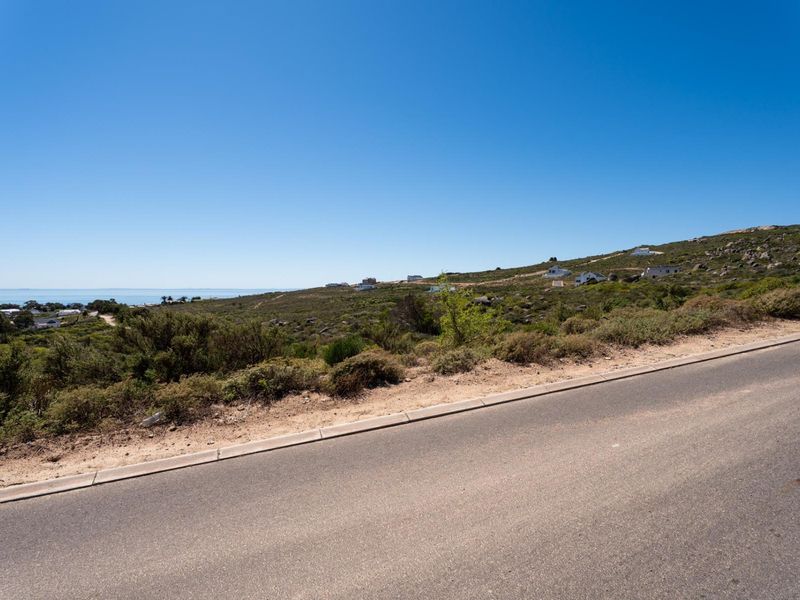 A scenic view of the coastal landscape and surrounding hillside from the adjacent paved road.
