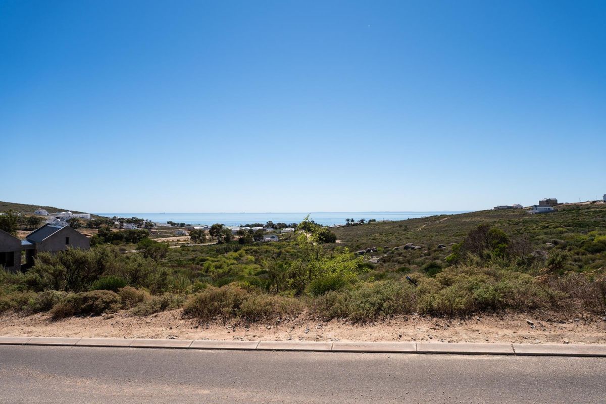 A scenic view of the coastal landscape and ocean horizon from the paved road, showcasing the natural surroundings of the vacant residential land.