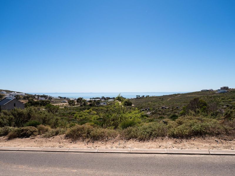A scenic view of the coastal landscape and ocean horizon from the paved road, showcasing the natural surroundings of the vacant residential land.