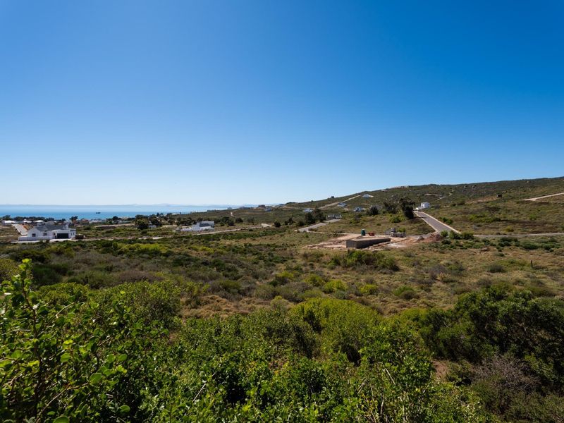 A wide-angle view of the coastal landscape and surrounding residential area, showcasing the natural terrain and distant ocean horizon.